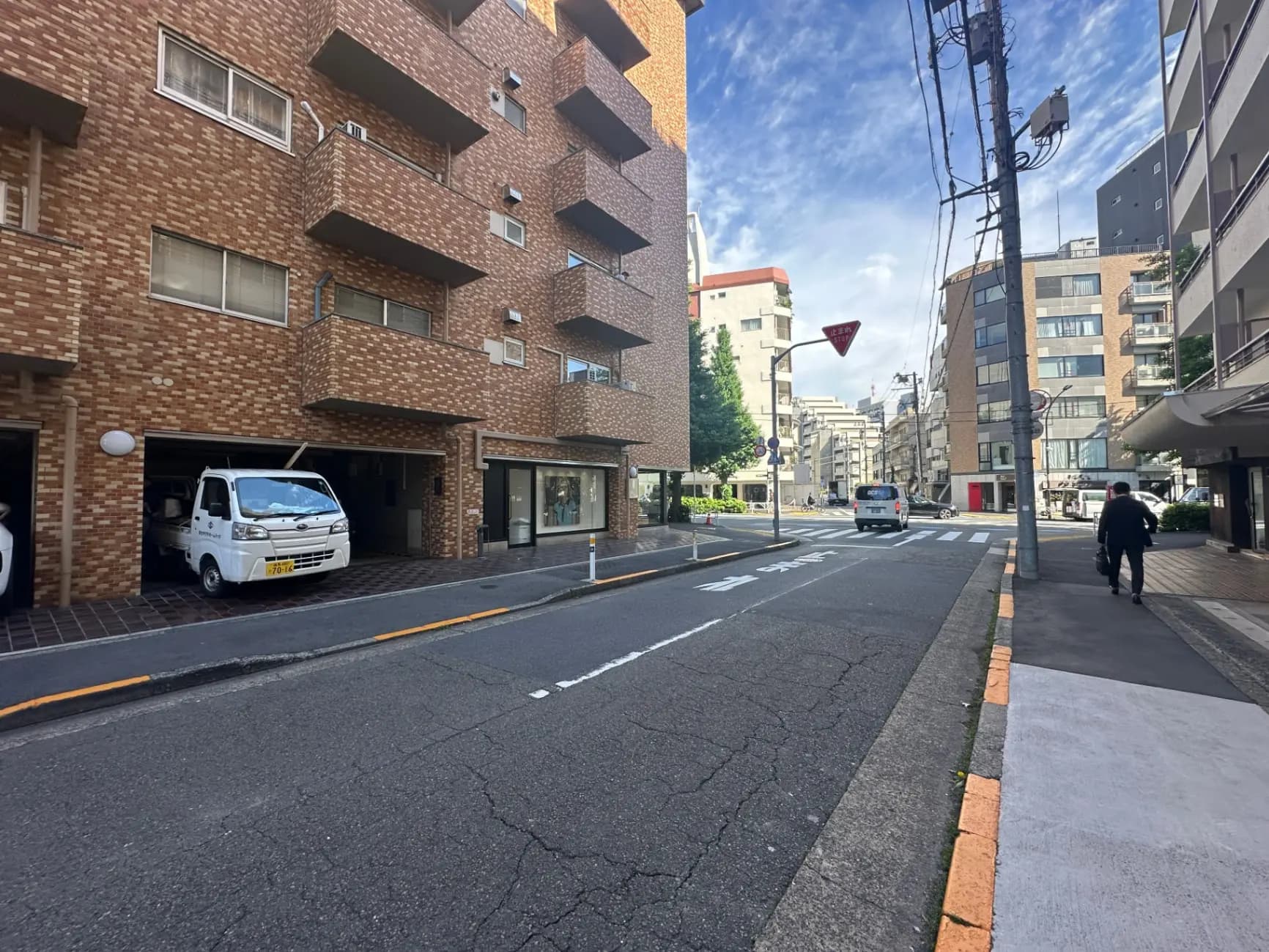 晴れた日の都市の住宅街、煉瓦造りの建物と歩行者、交通標識が見える街角