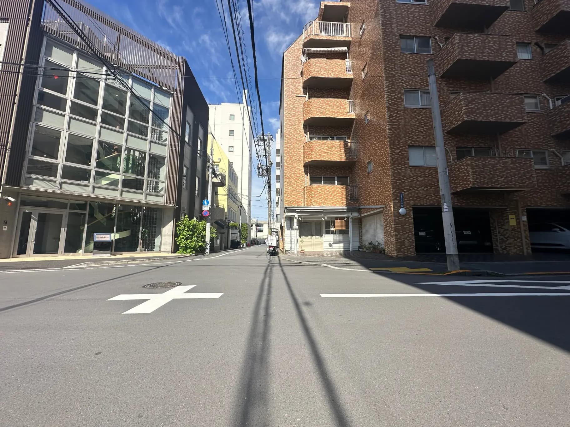 快晴の日に撮られた都市の交差点、アスファルトの道路、建物と自転車の通行