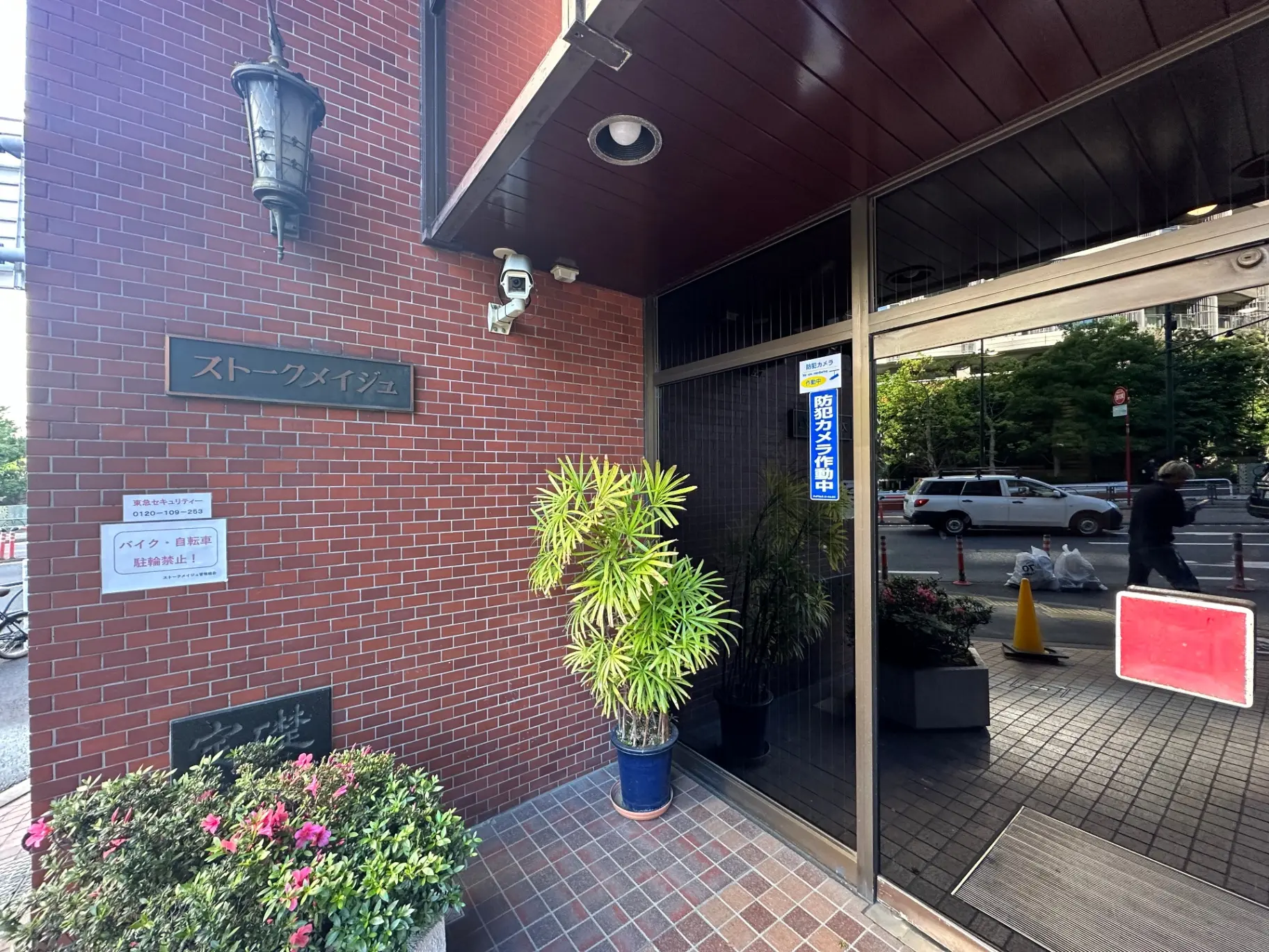赤レンガ造りのオフィスビルエントランス、植物の装飾と街角の景色