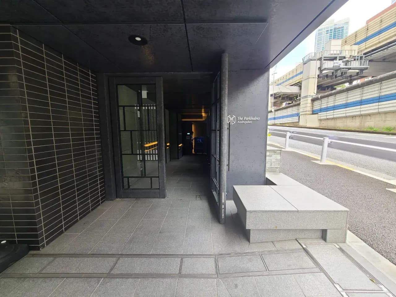モダンな都市のビル入口、コンクリートのデザイン、背景に高速道路と都市の建築物