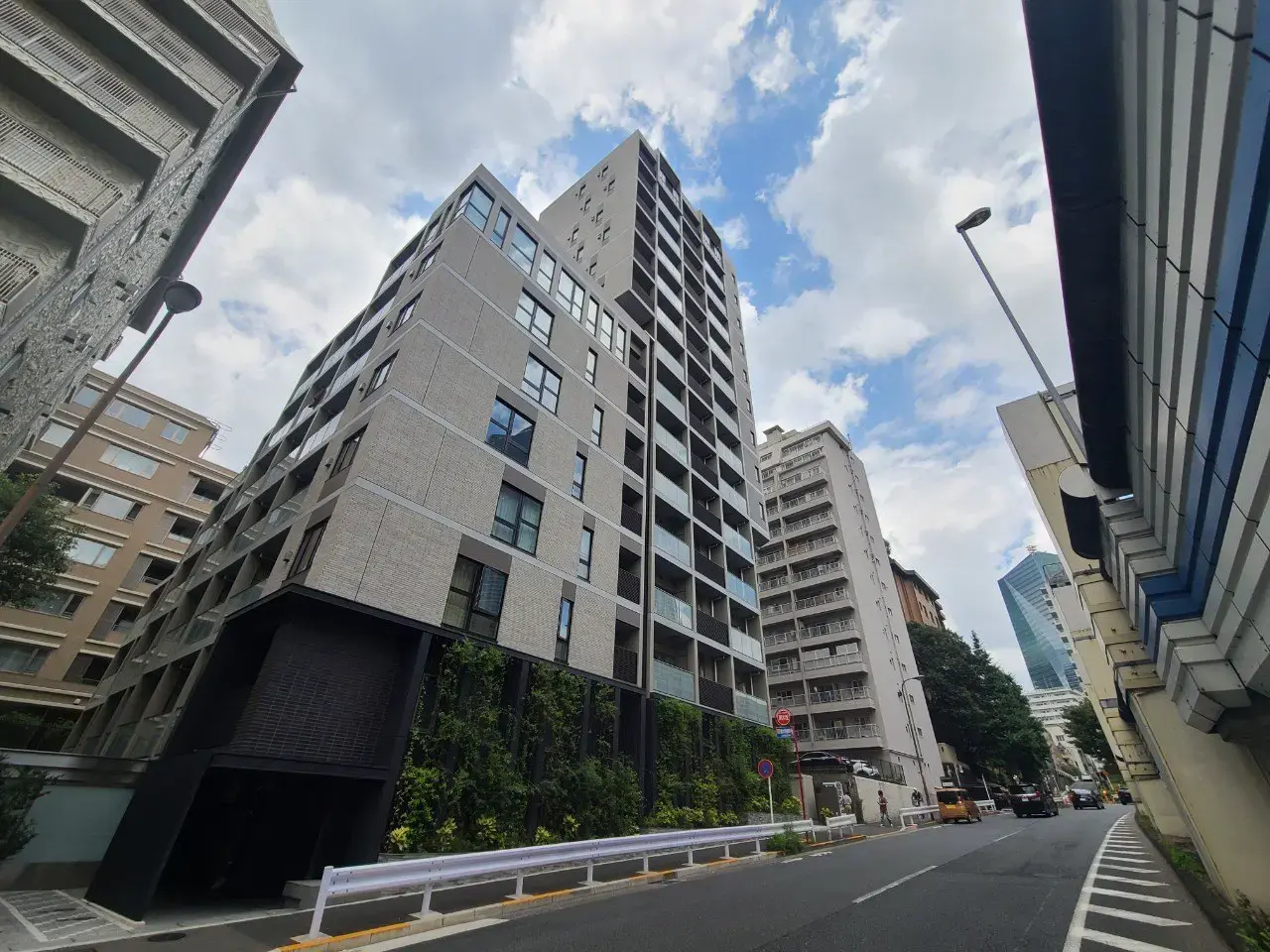 現代的なデザインの都市型マンション、晴れた日の青空、周りには高層ビルと低層ビルが混在