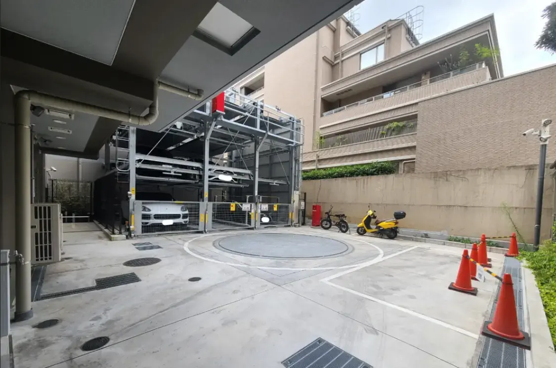自動車用メカニカル式立体駐車場とターンテーブル、背景には建物と自転車が見える都市の光景