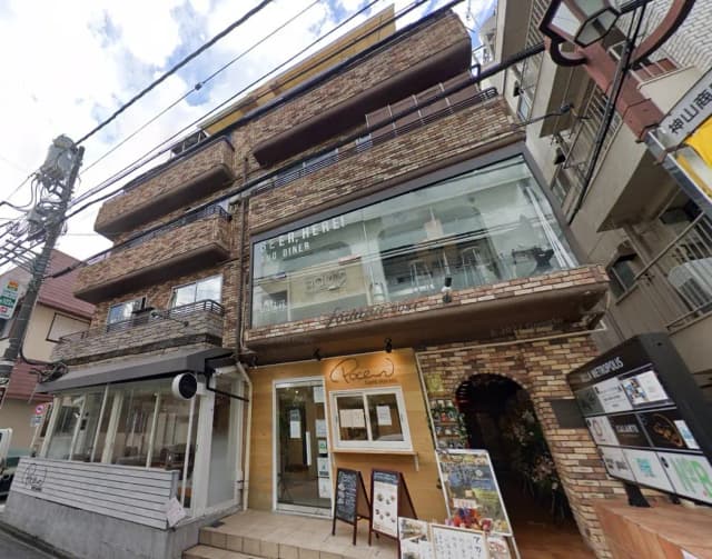 街角のレンガ造りの多層ビル、一階にカフェとダイナーの店舗があり、都会的な雰囲気のある風景