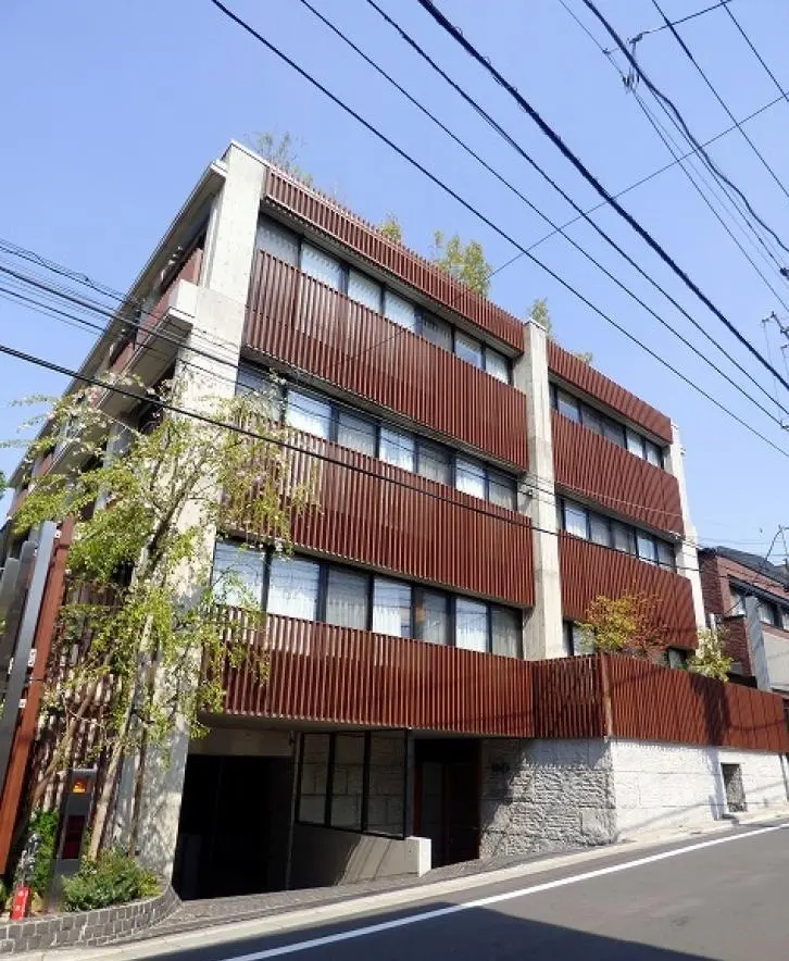 モダンな外観のアパートビル、木目調のバルコニー、街路樹が植えられた歩道