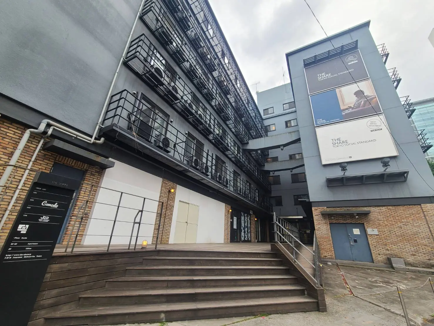 外階段付きのモダンな黒いビル、都市のオフィスやアパートメントの外観、屋外広告のあるファサード