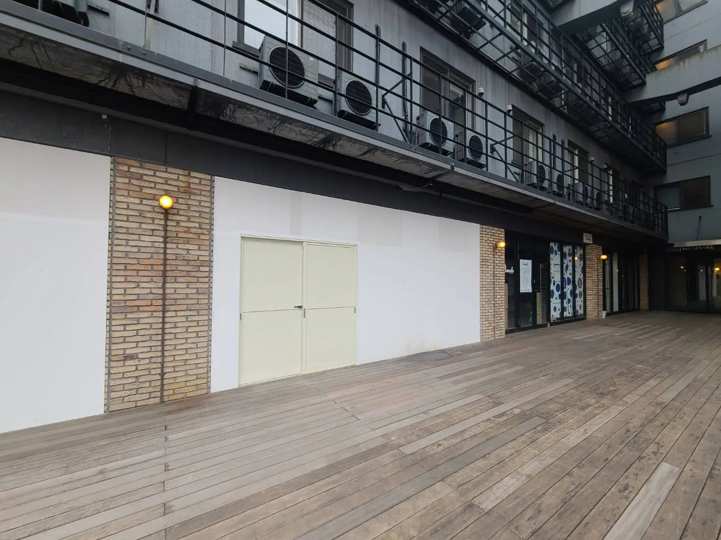 モダンな建築スタイルの屋外通路、木製デッキと壁面照明、ビルの共用バルコニー