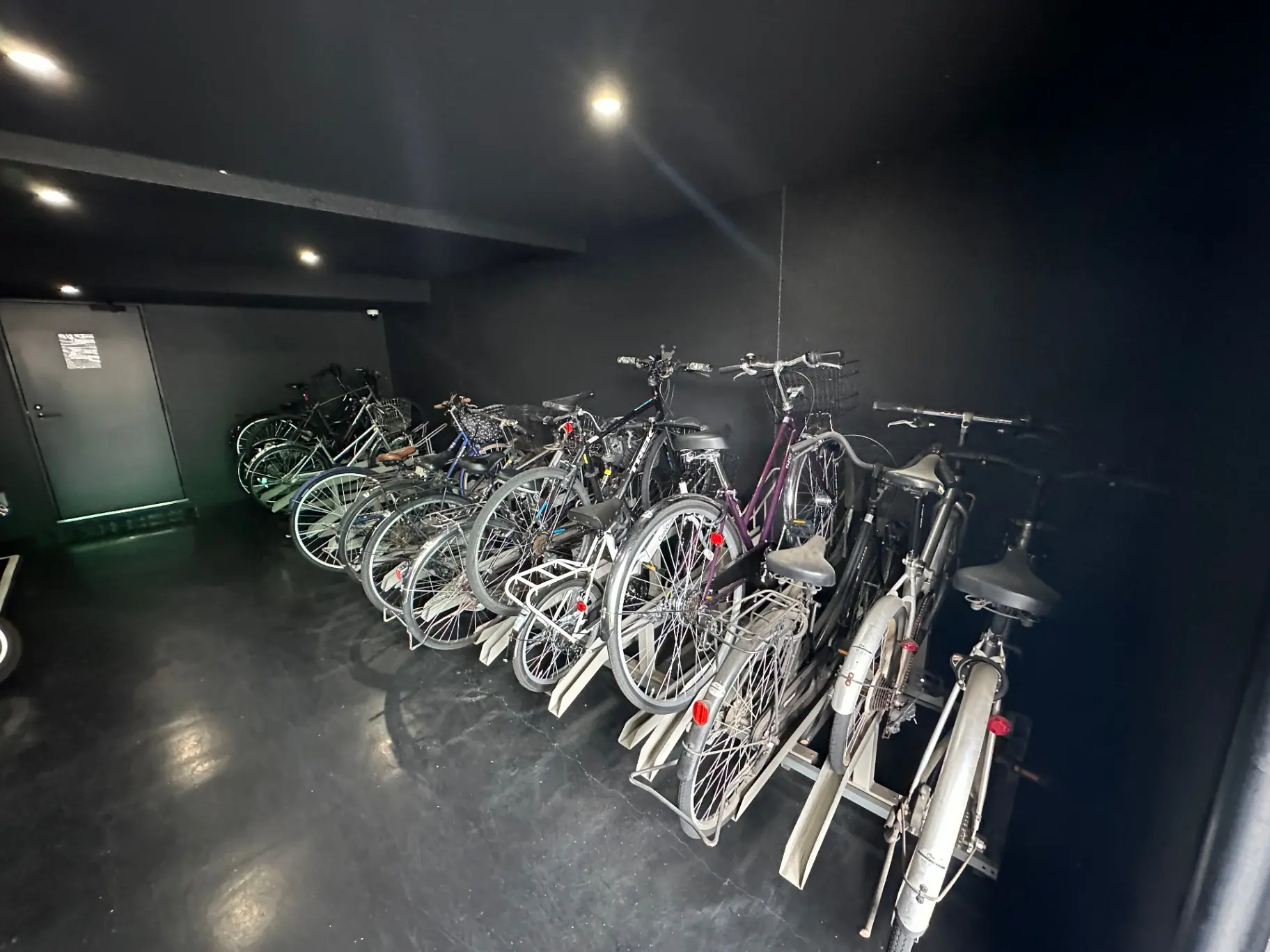 屋内の自転車駐輪スペース、照明が設置された黒い壁と床
