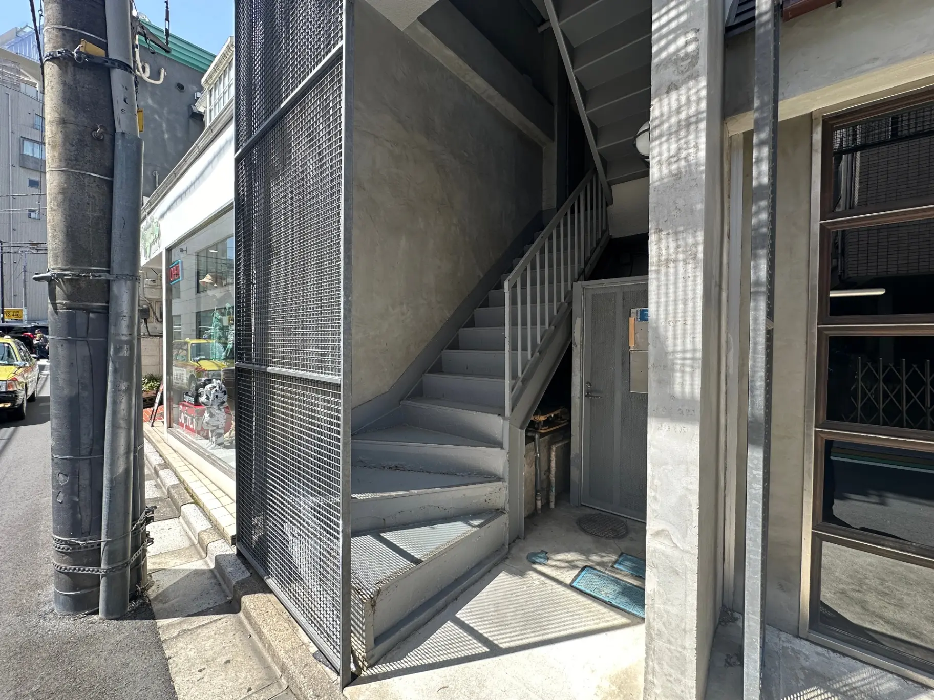 都市の建物の非常階段、日差しが差し込むコンクリートの階段とメタルの手すり