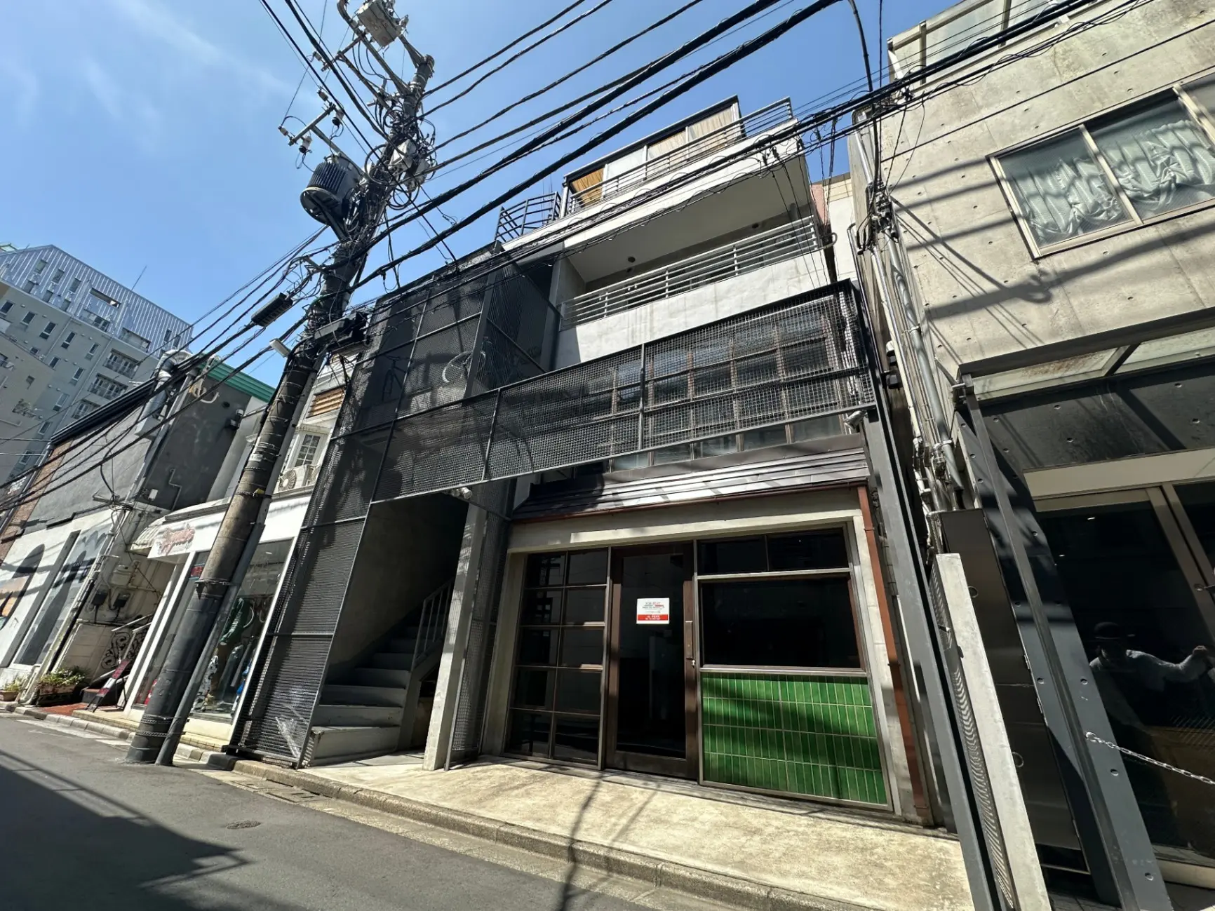 日差しが明るい街角のビル風景、電線が交差している都市の光景