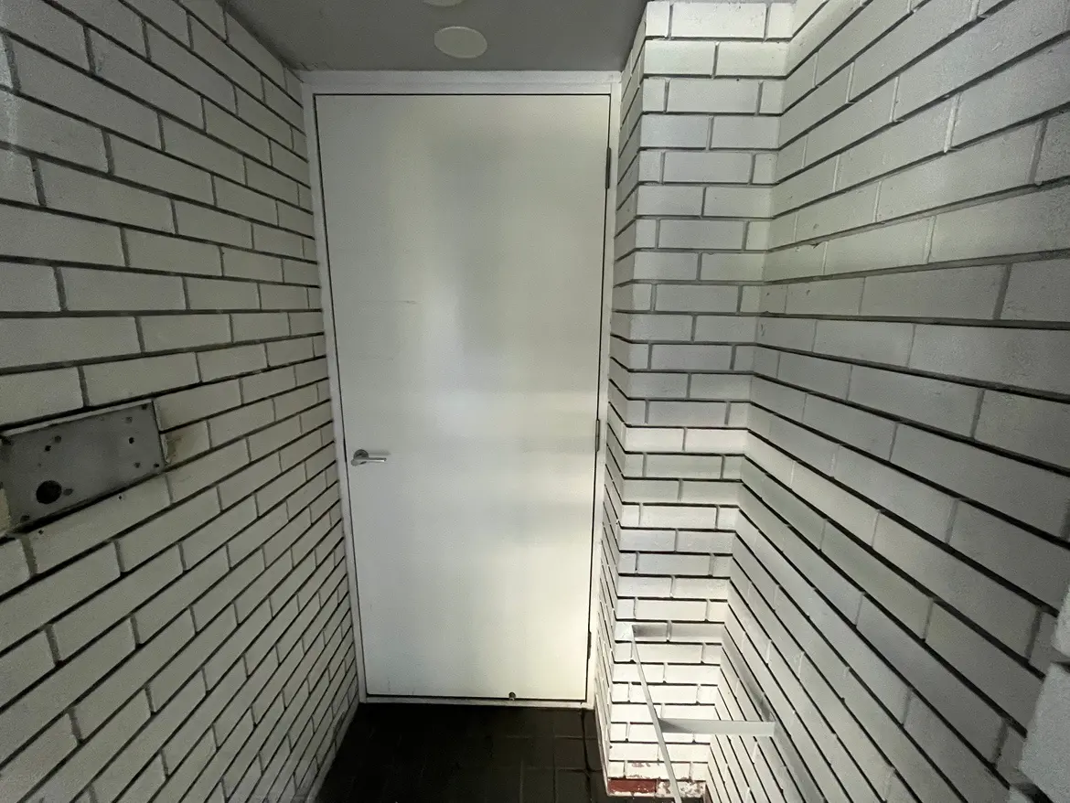 - 白いレンガタイルの壁とドアがある狭い廊下、おしゃれでクリーンなデザインのエントランス