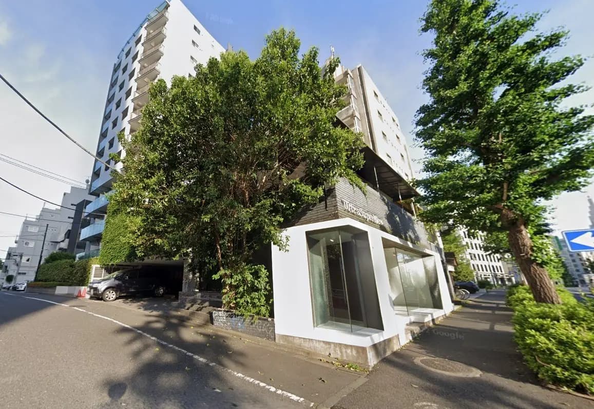 都市部に位置するモダンな建物の外観、広い歩道と緑豊かな樹木がある景観