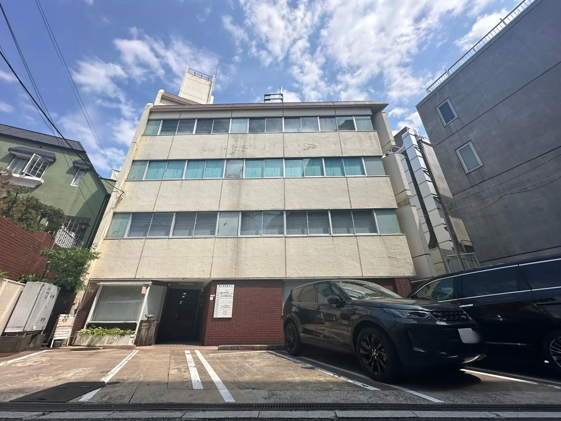 都会的な環境にあるマンションの外観、晴れた日に撮影された駐車スペースあり