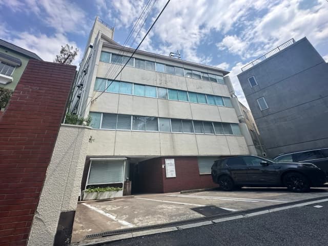 日中の都市風景、モダンな外観のオフィスビルまたはアパート、駐車場にSUV車、晴れた空