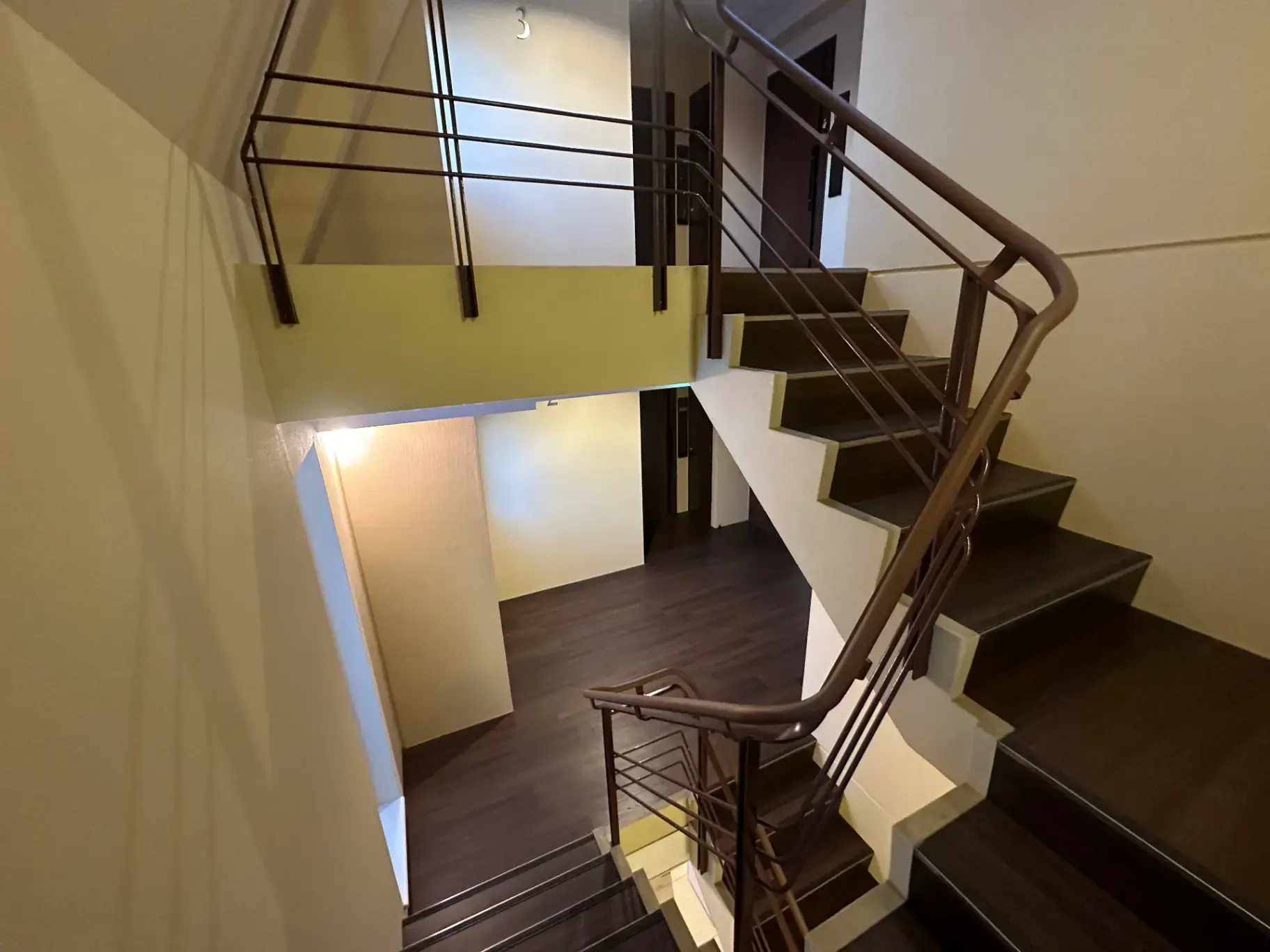 モダンな住宅の内部階段、木製ステップと金属製手すり、暖かい照明とクリーム色の壁