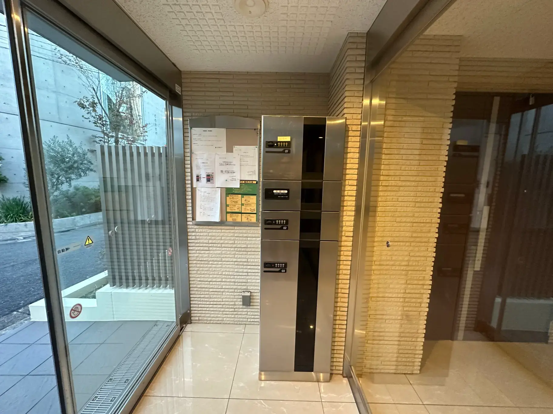 建物のエントランスホールにある郵便受けと掲示板、自動ドアと清潔な内装