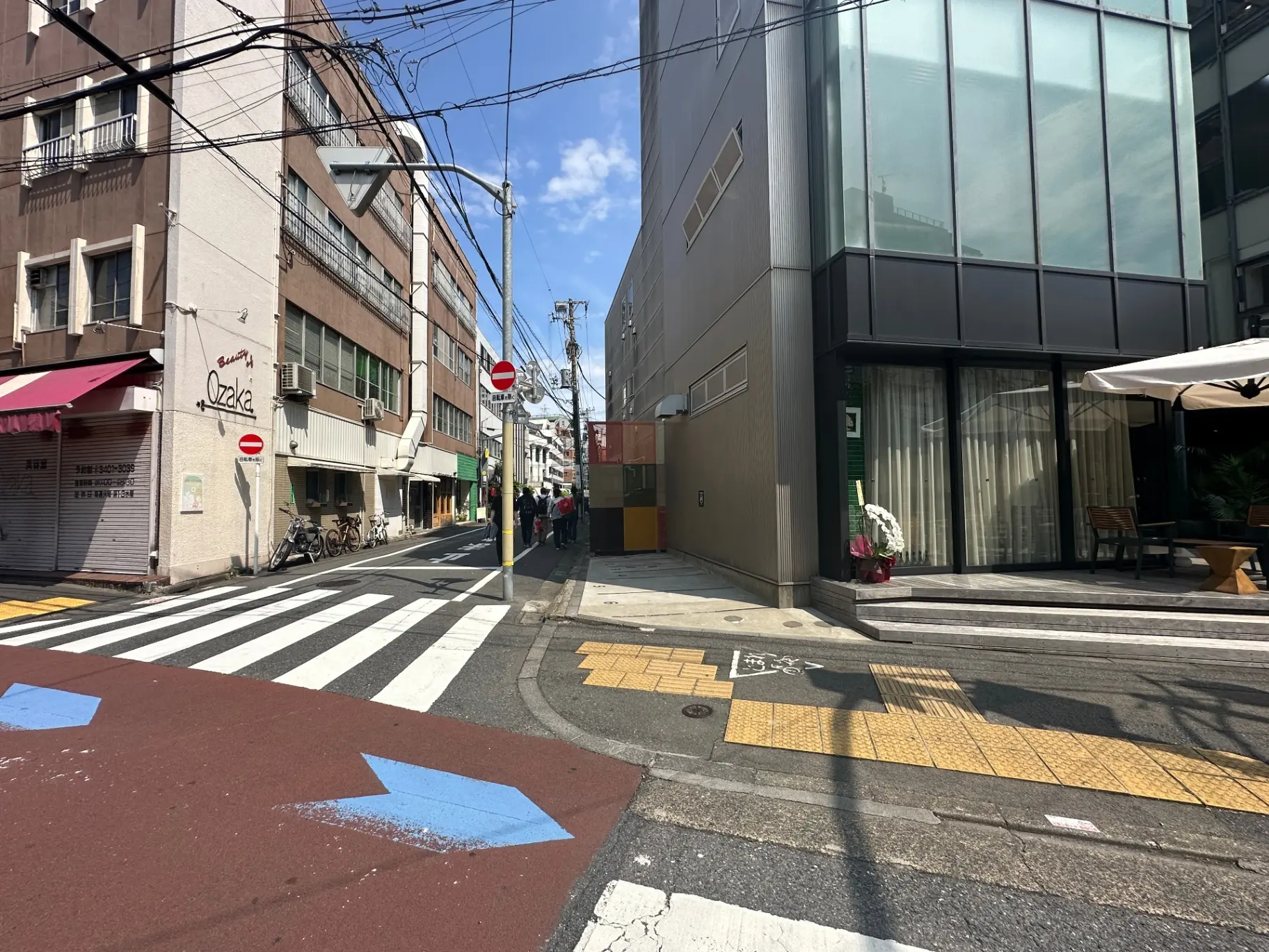 晴れた日の都市風景、歩道と横断歩道、カフェのテラス席、街角の建物と商店街