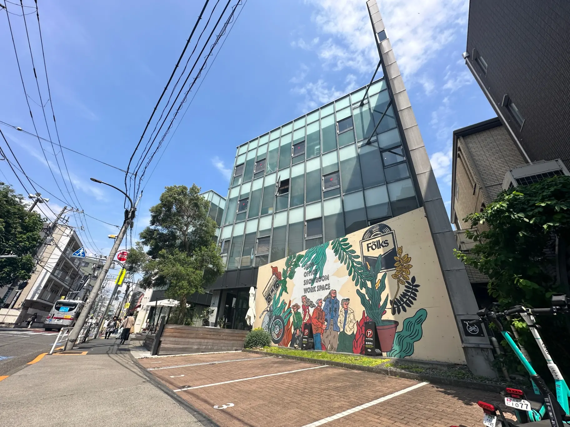 都会のコーナーにあるモダンなガラス張りの建物とカラフルな壁画、晴れた日の街角の景観