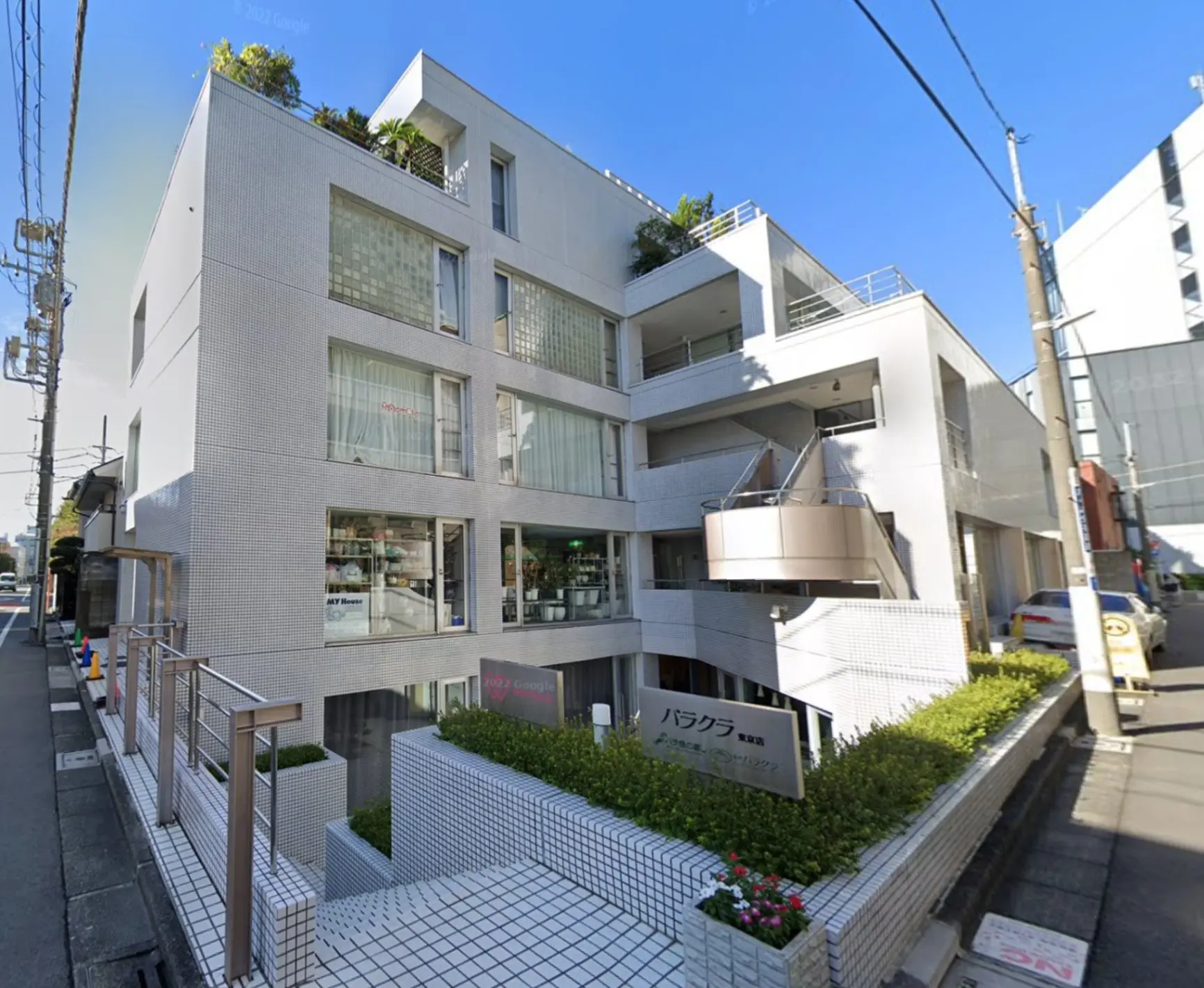 現代的な外観のマンションビル、都市の角地に位置する、植栽付きのバルコニーとクリアなガラス窓