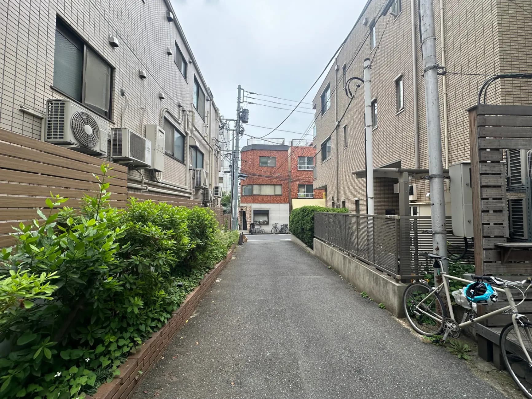 日本の住宅街の狭い道、自転車が駐輪されている、周囲には低層のアパートと電柱