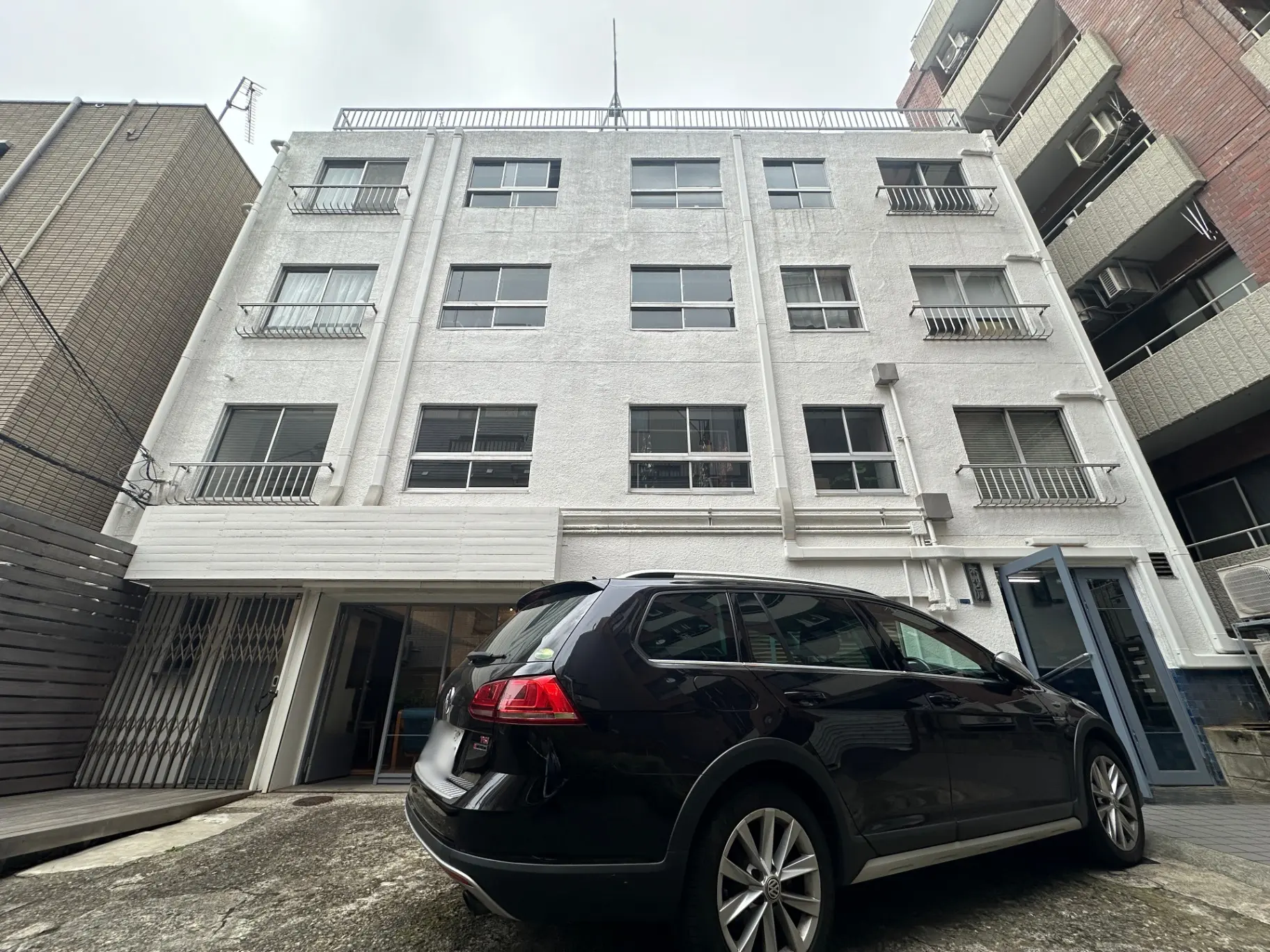 白い外壁が特徴的な都会のマンションとそばに駐車された黒いSUV車