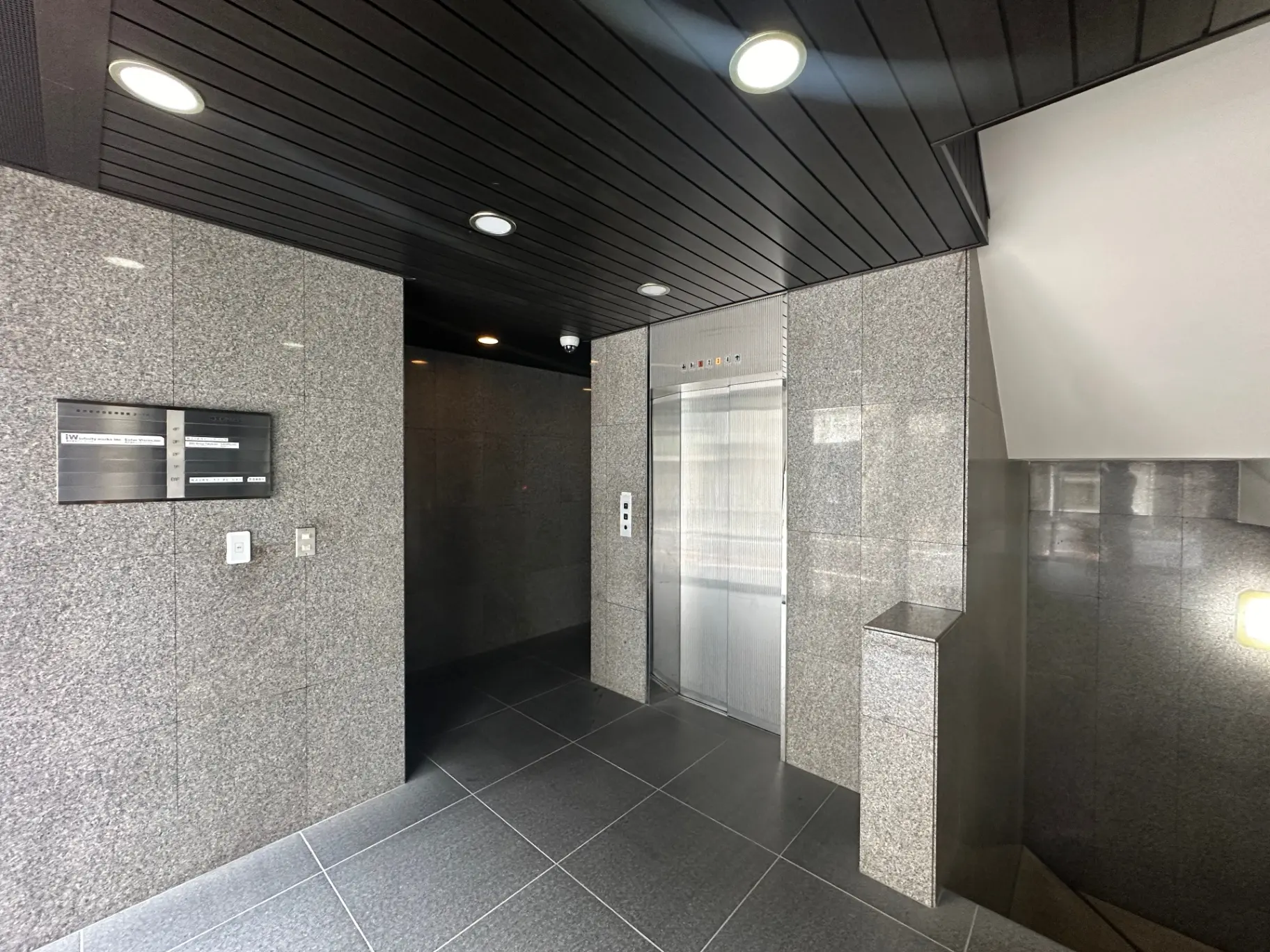 モダンなマンションのエントランスホール、エレベーターと宅配ボックス、天井と壁の照明