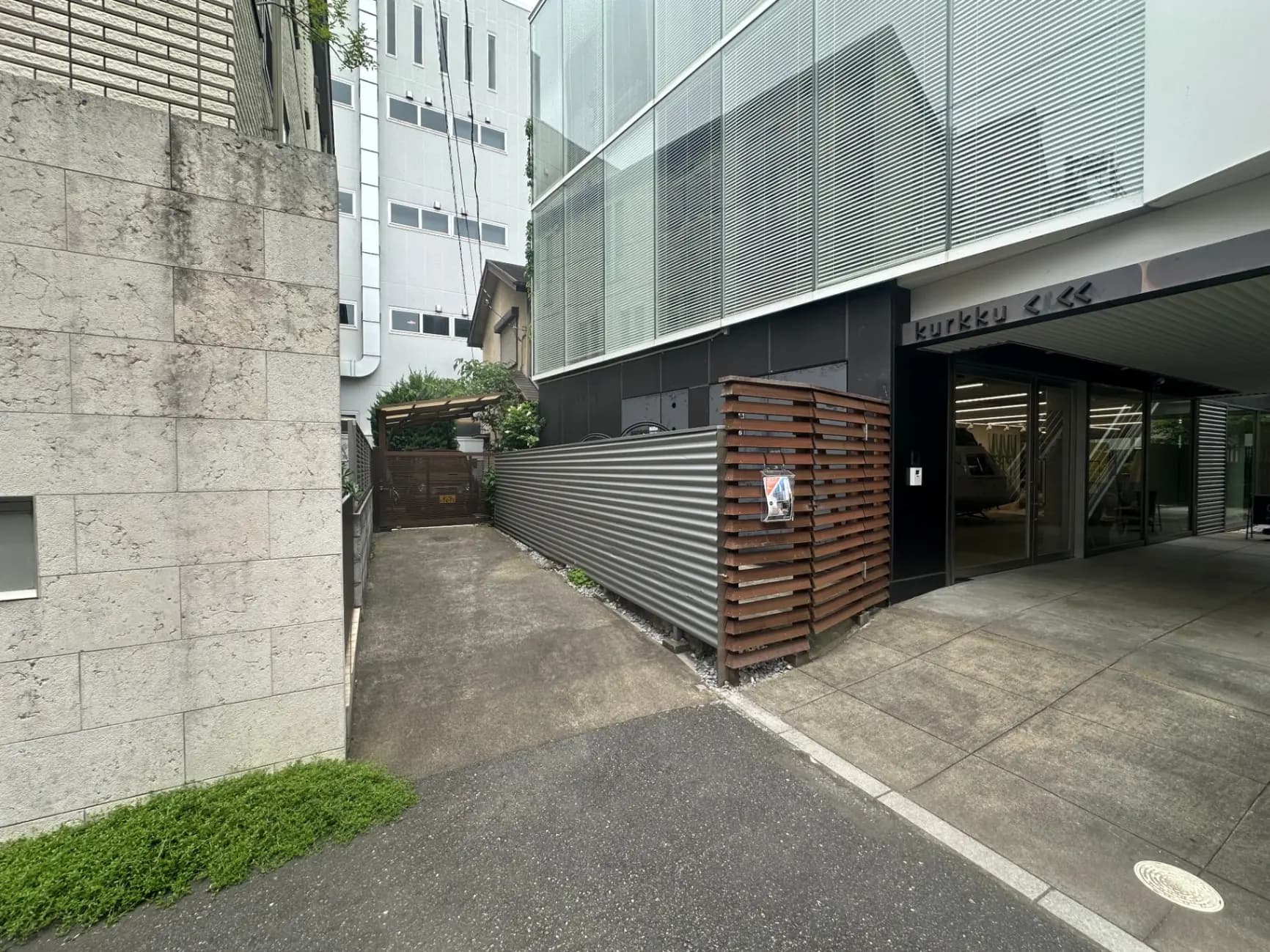 現代的なオフィスビルのエントランス、屋外に木とガラスのファサード、地面に配されたタイル