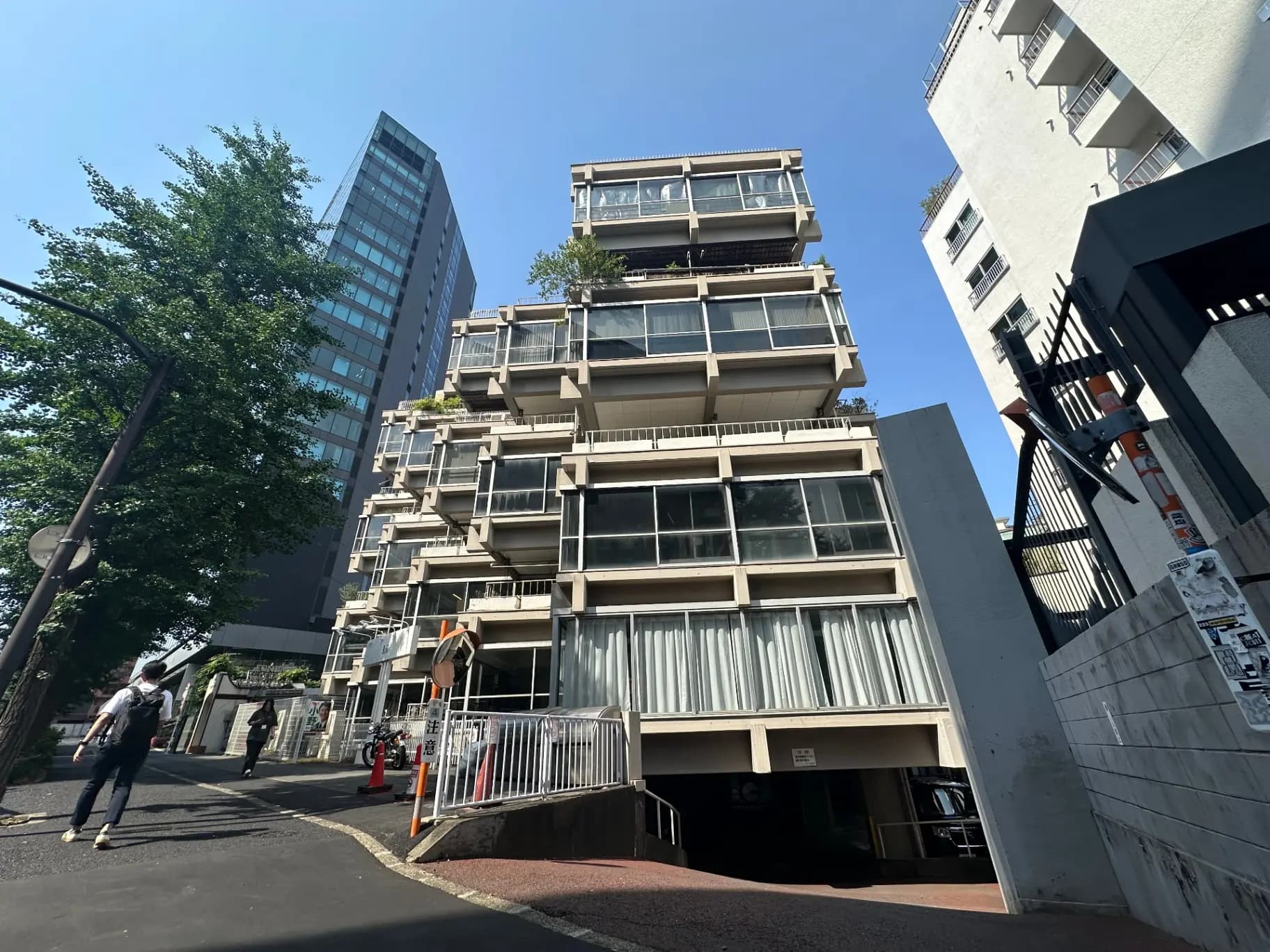 日差しが差し込む晴天の日の都市風景、歩行者が通る舗装された道と現代的なビルの外観