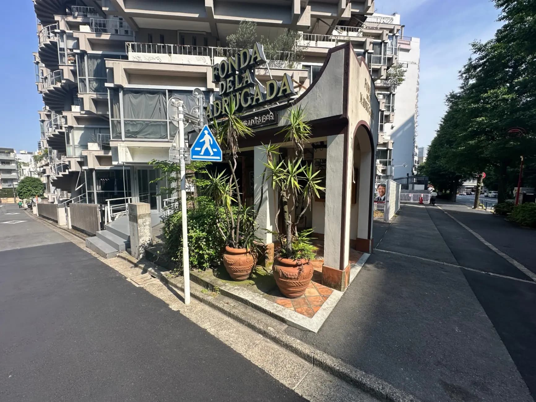都会的な通りにあるモダンな外観の建物、歩道と横断歩道の標識が見える都市風景