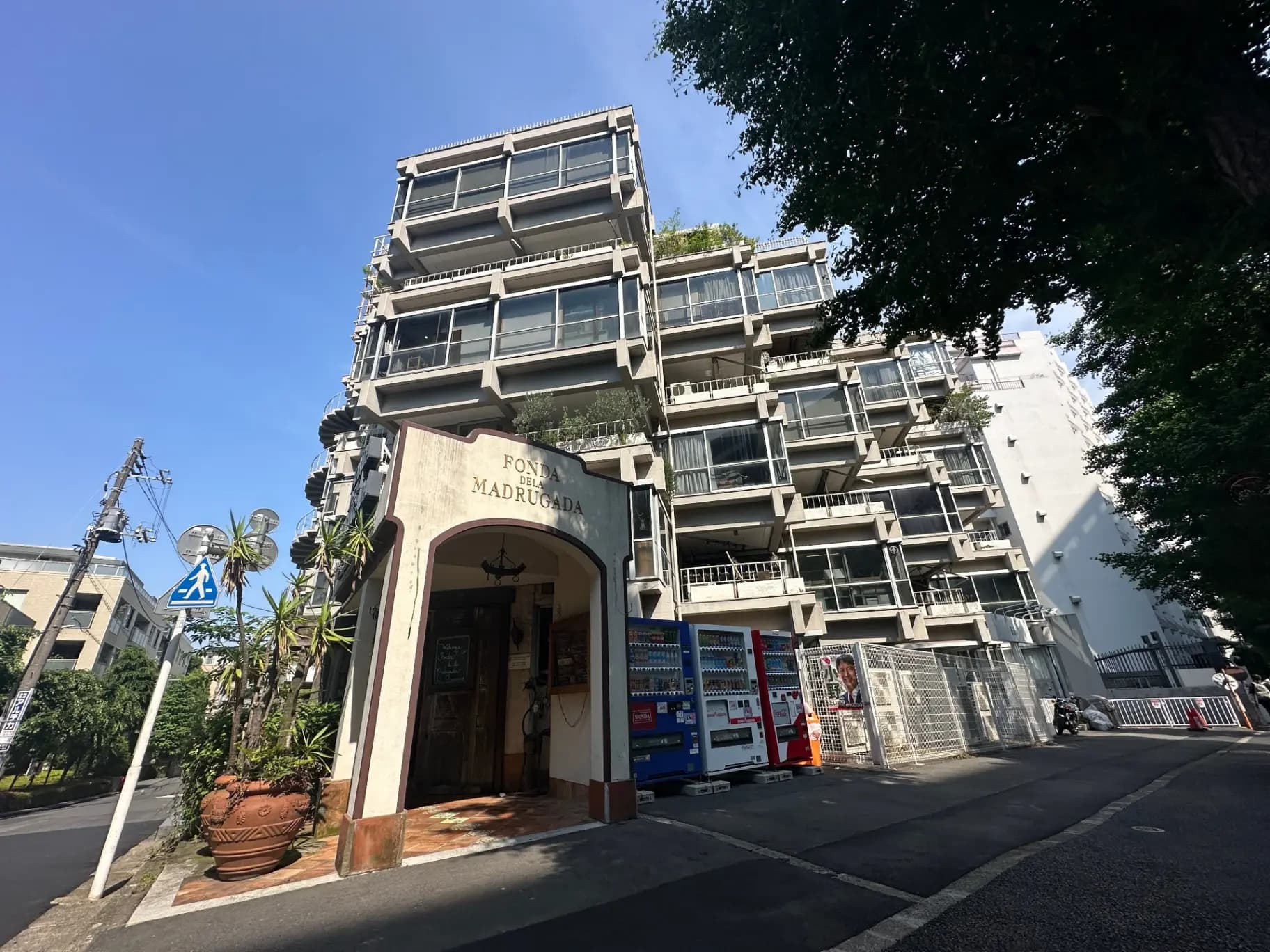 現代的なマンションとレストランの外観、晴れた日の都市風景、街路樹と歩行者横断表示