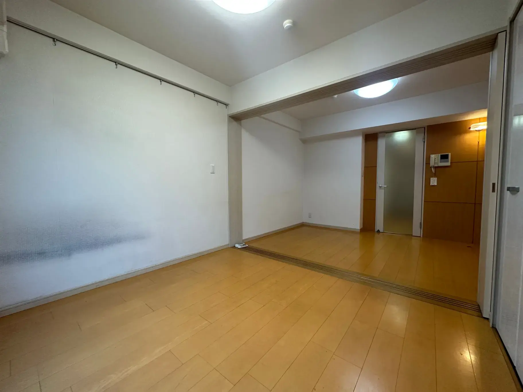 シンプルなデザインの空の部屋、木製のフローリング、白い壁、明るい照明のインテリア