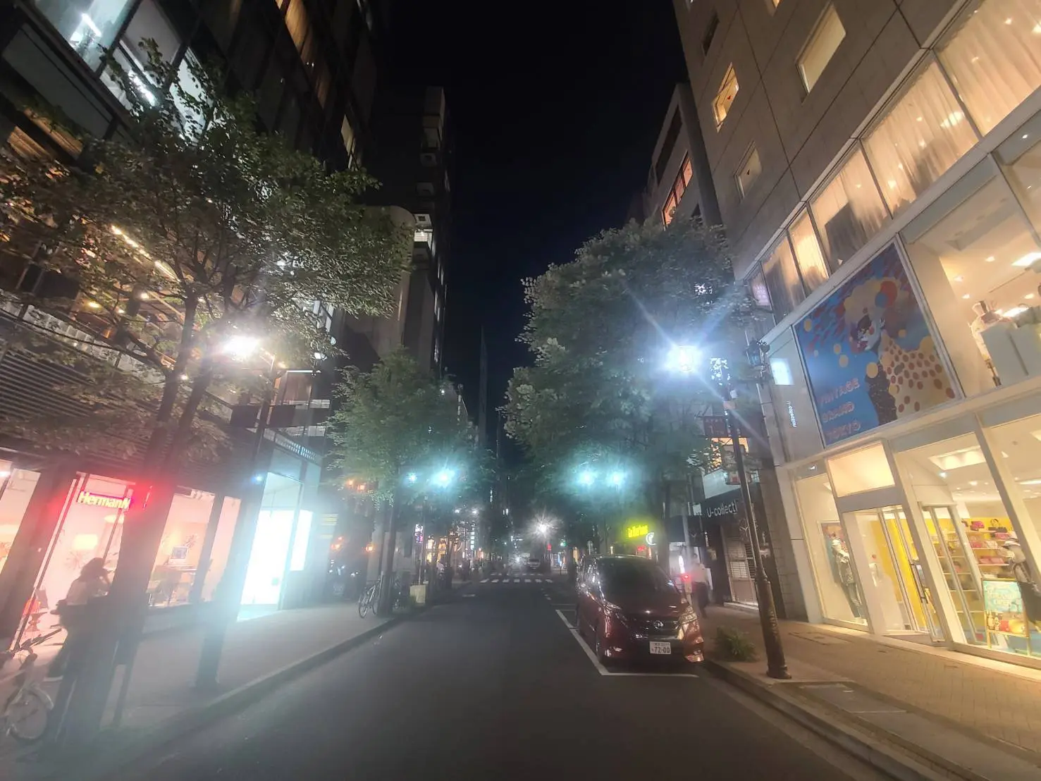 夜のショッピング街、明るく照らされた店舗と通り、歩行者と駐車している車