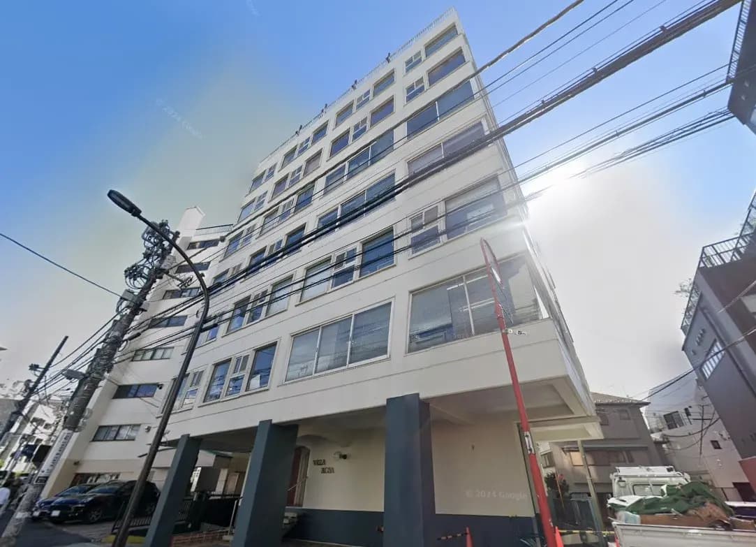 日中の都市環境で撮影されたモダンなマンション外観、電線と建物のファサードが見える街角ストリートビュー