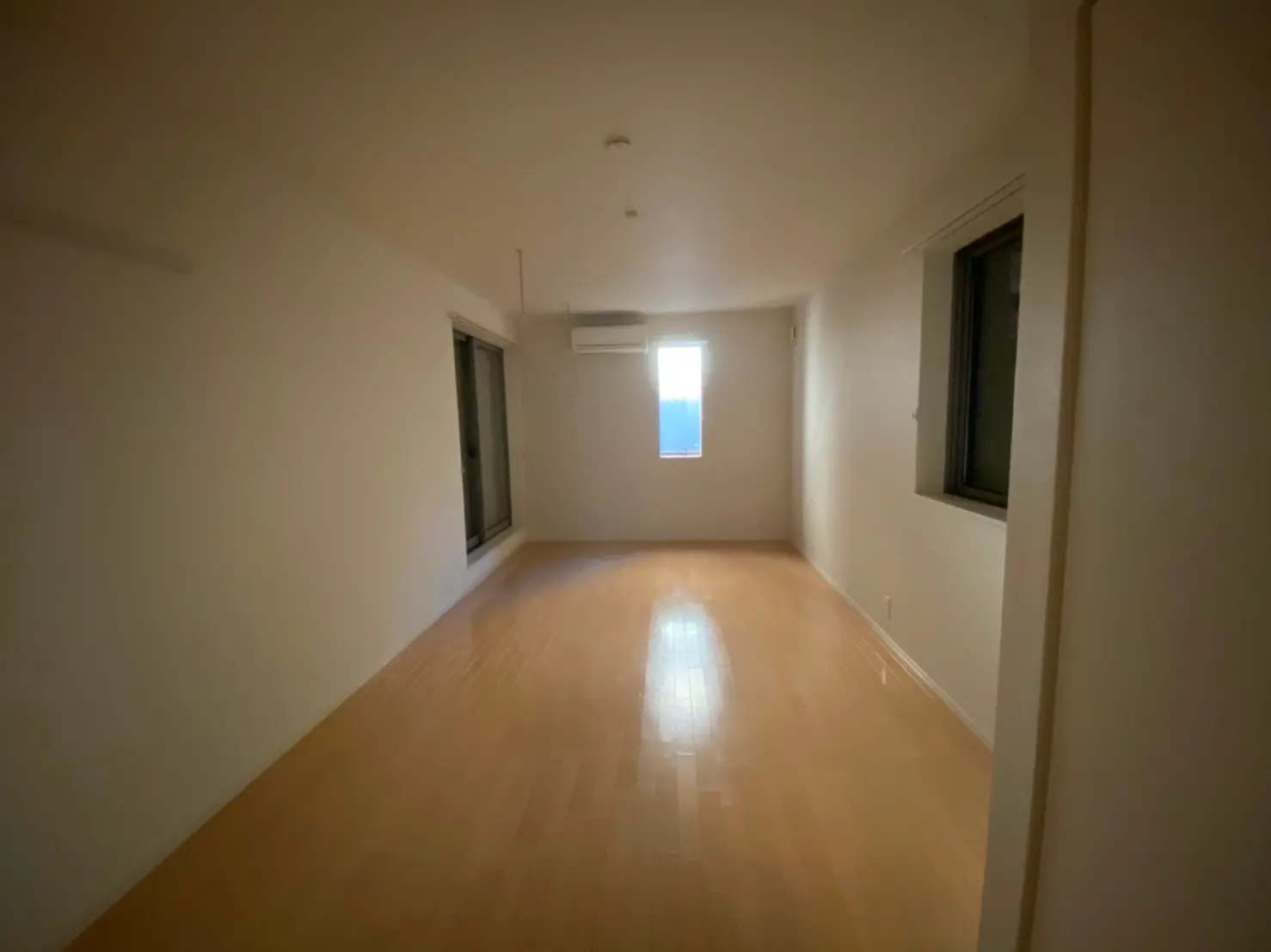 シンプルなデザインの空の部屋、木製フローリングと白い壁、自然光が差し込む窓