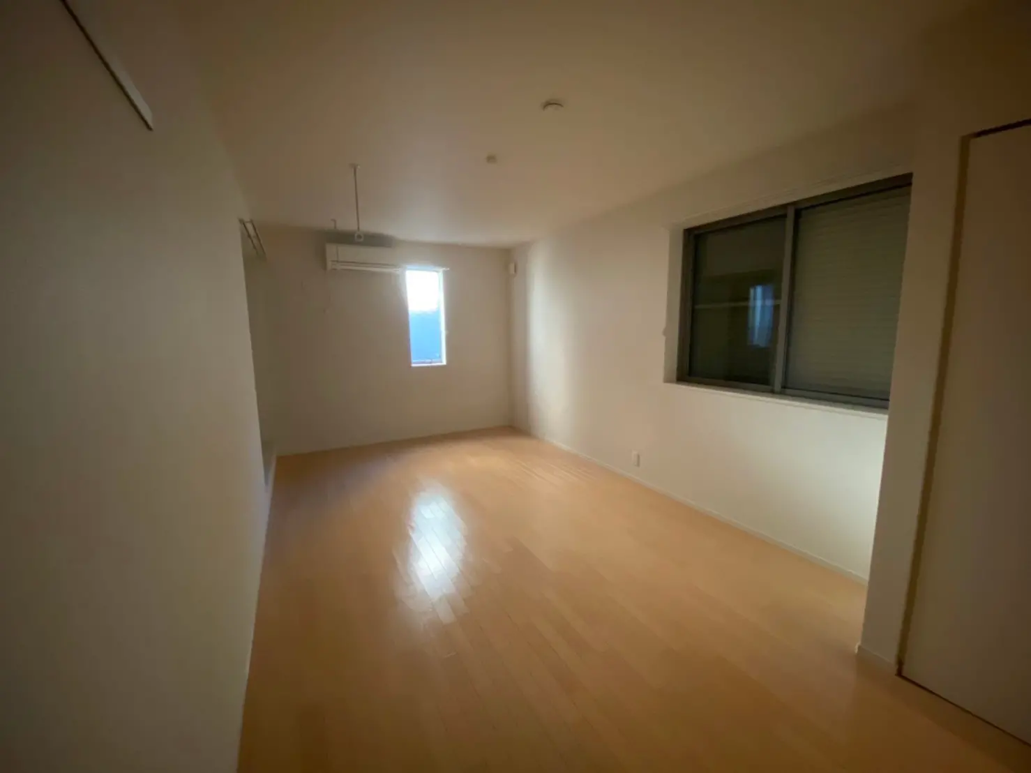 シンプルな内装の空き部屋、木製フローリング、自然光が差し込む小窓