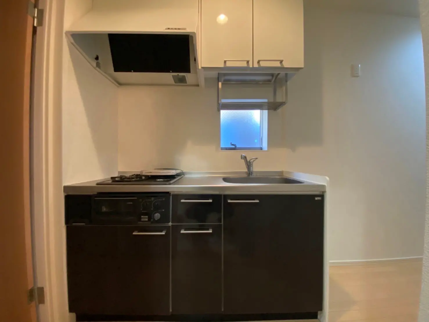 コンパクトなキッチン、ブラウンのキャビネットとガスコンロ、窓から自然光が差し込む