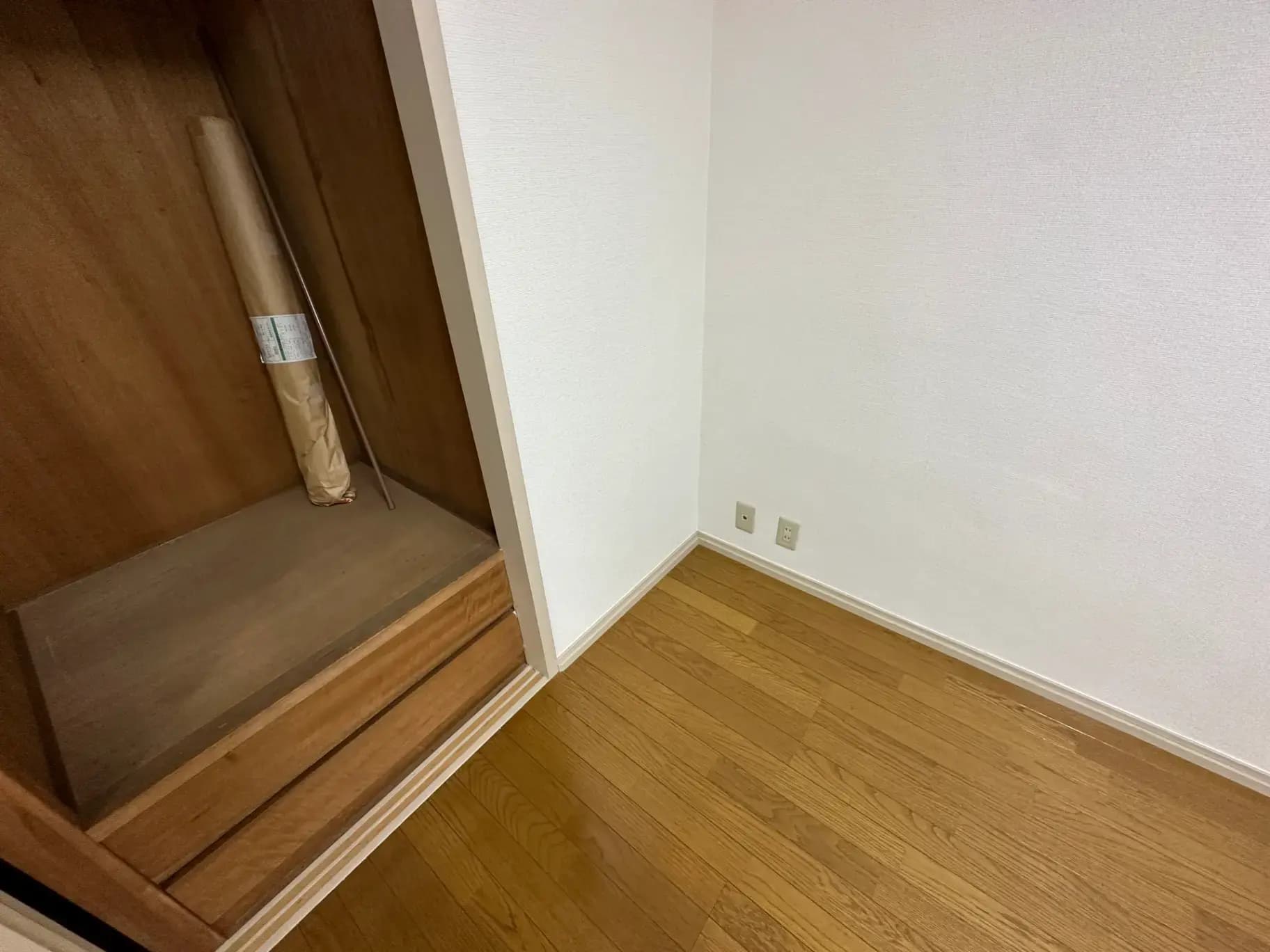 コンパクトな木製の棚と清潔な白い壁が特徴の角部屋