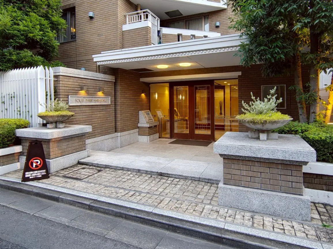 - ソレイパーク原宿のエントランス、モダンな外観と植栽、屋根付きの入り口、明るい照明がある立派な入口の風景
