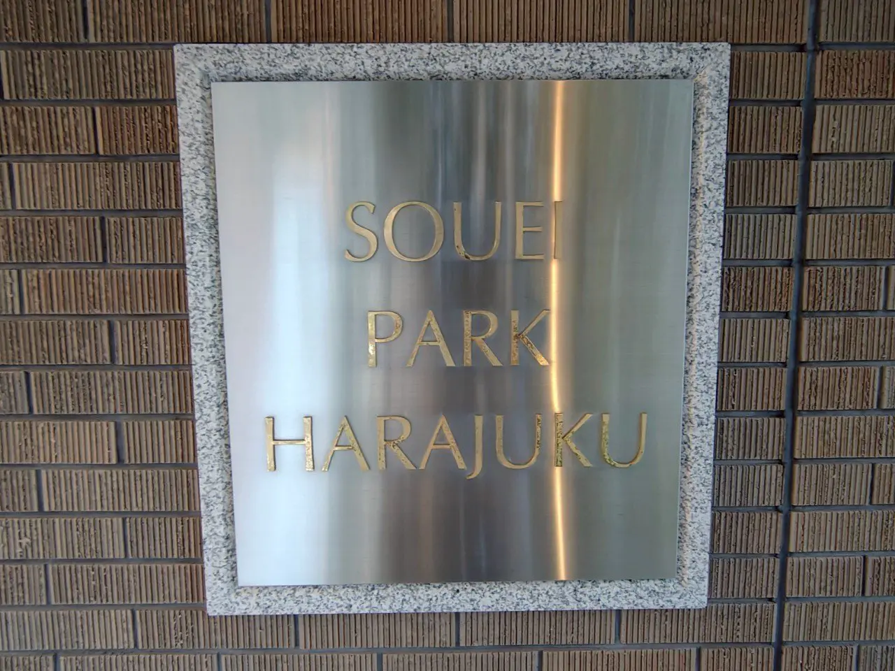 - 原宿にある「SOUEI PARK」の金色のサインプレート、シルバーの背景と石材のフレームが特徴的なデザイン