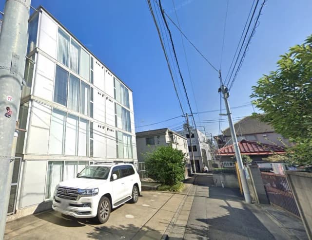 現代的な外観のオフィスビルと白いSUV、晴れた日の市街地風景