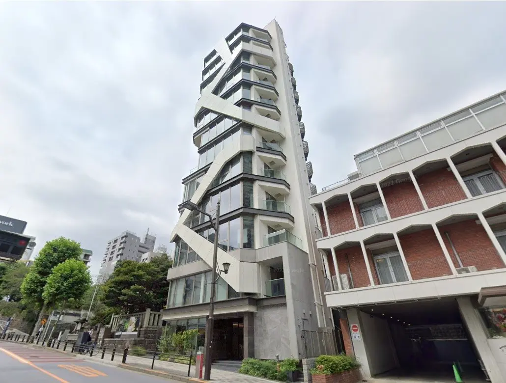 ユニークなデザインの都会的なマンションビル、歩道と緑豊かな樹木がある街角