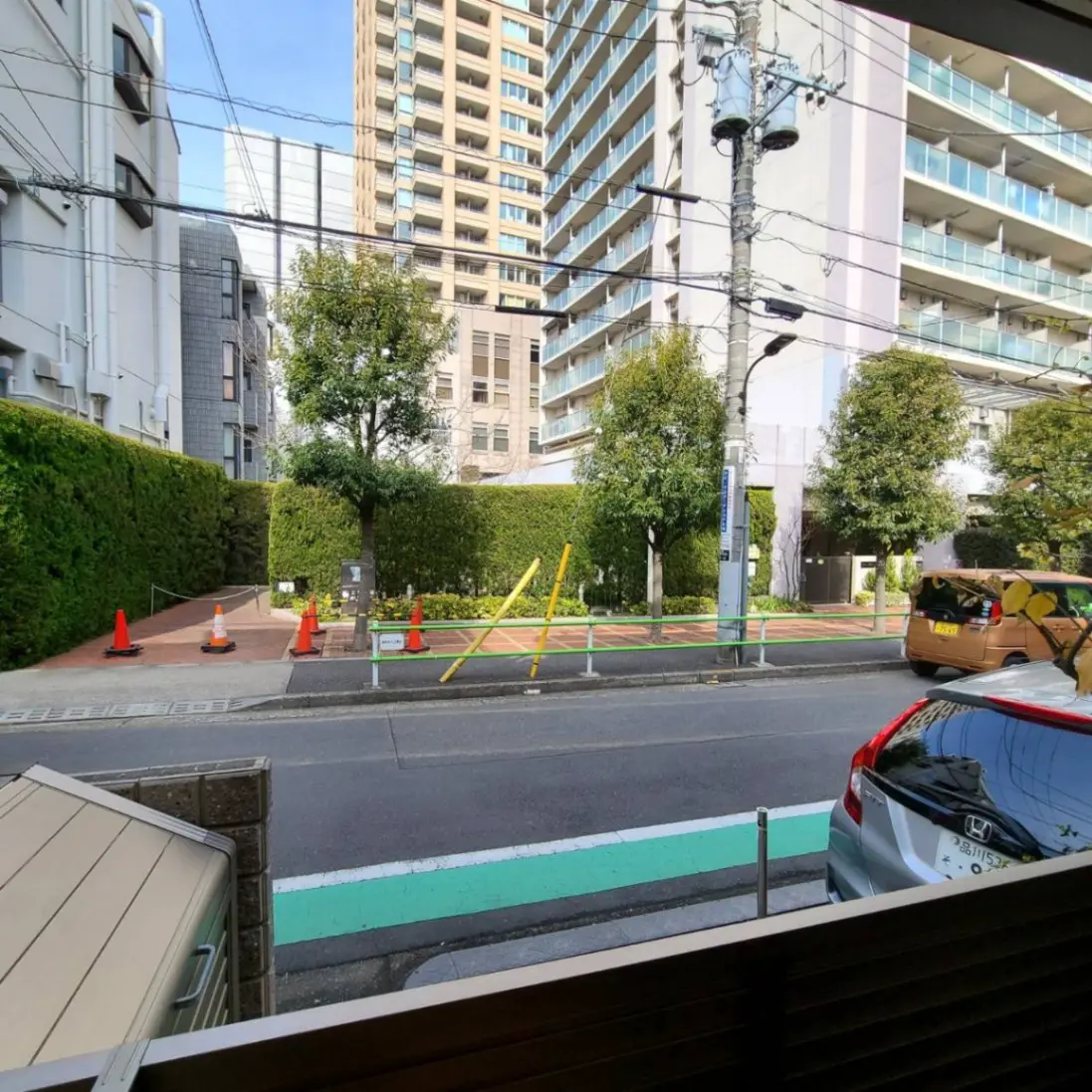 窓からの都会の風景、道路とマンション、緑の道路標識、晴れた日の明るい光