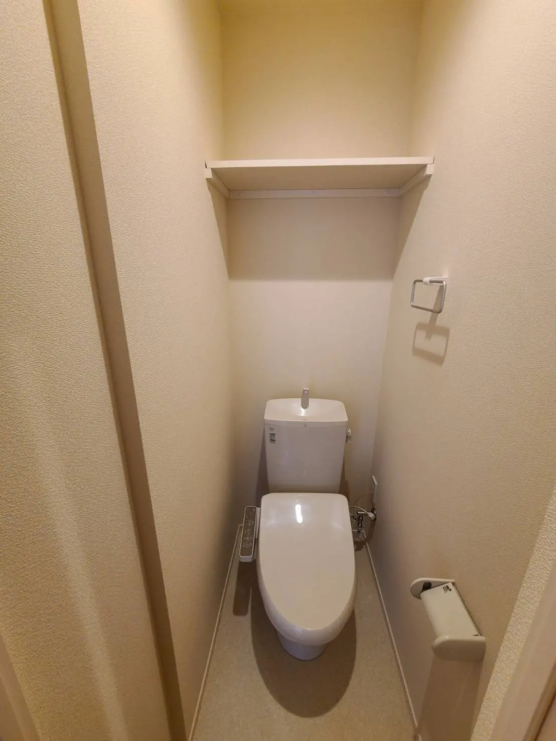 画像：狭いスペースに設置された清潔な日本式トイレとトイレットペーパーホルダー