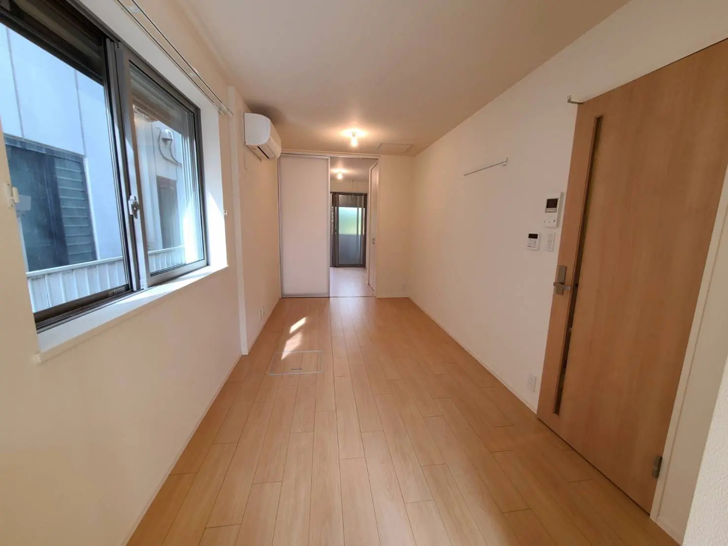 シンプルでクリーンなデザインの空の部屋、木製フローリング、白い壁、自然光が差し込む窓