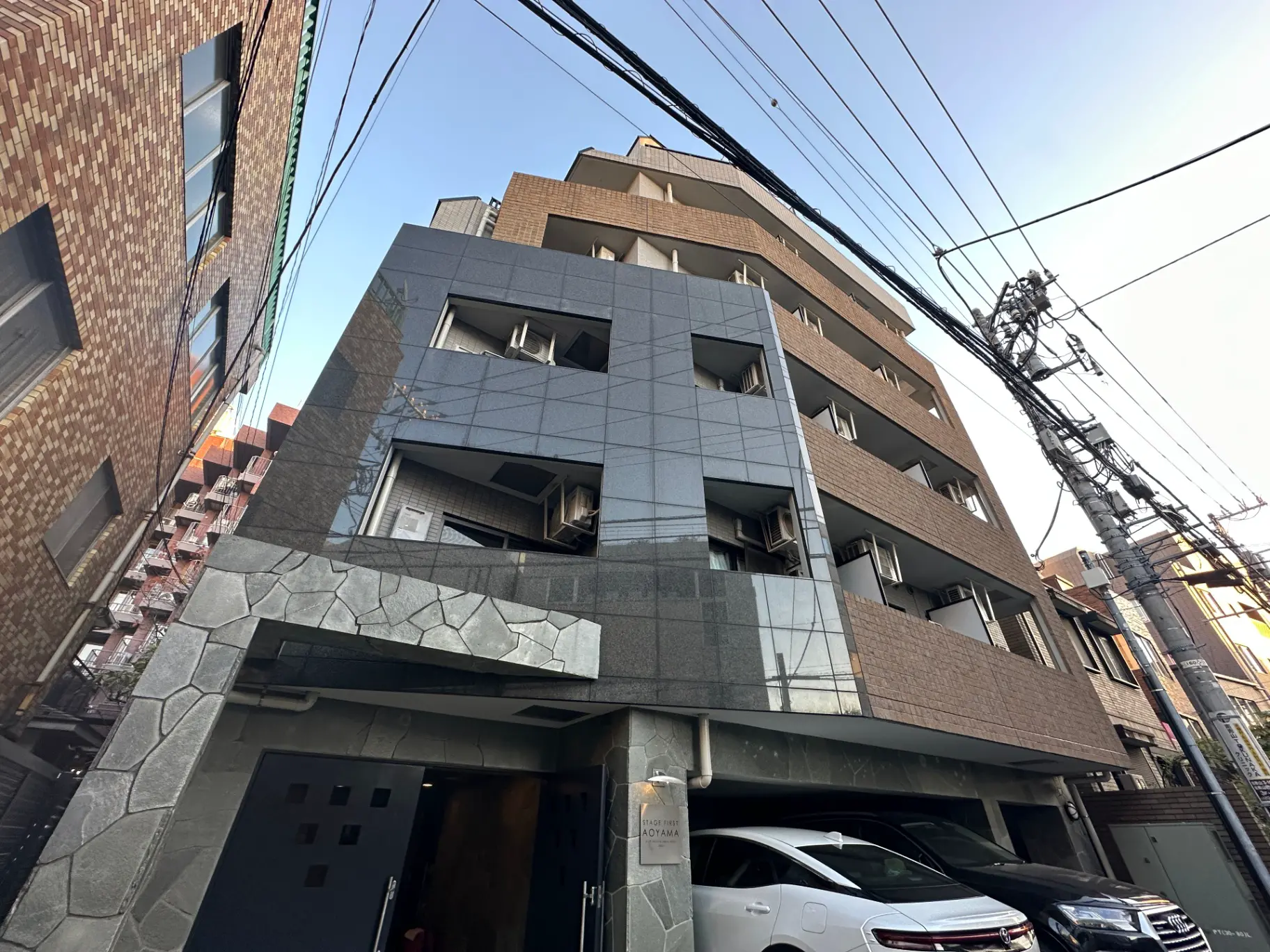 現代的な外観の都市型マンションビル、日本の狭い通りに建つ、電線が交差する景観