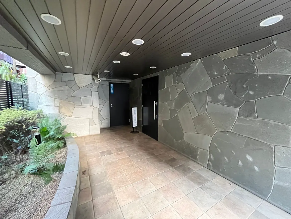 モダンな建物のエントランスホール、石の壁と天井に組み込まれた照明、小さな庭園と植物があるデザイン