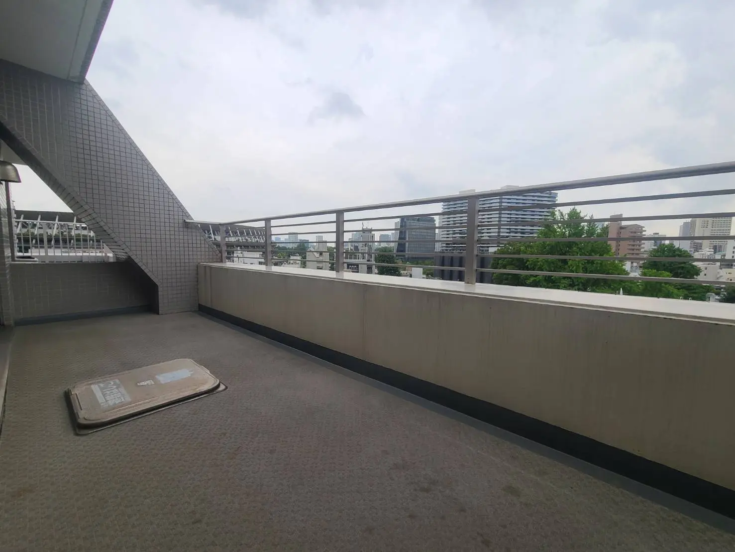 - 都市の眺望を楽しめるバルコニー、階段が隣接し、シンプルな床材が敷かれたスペース