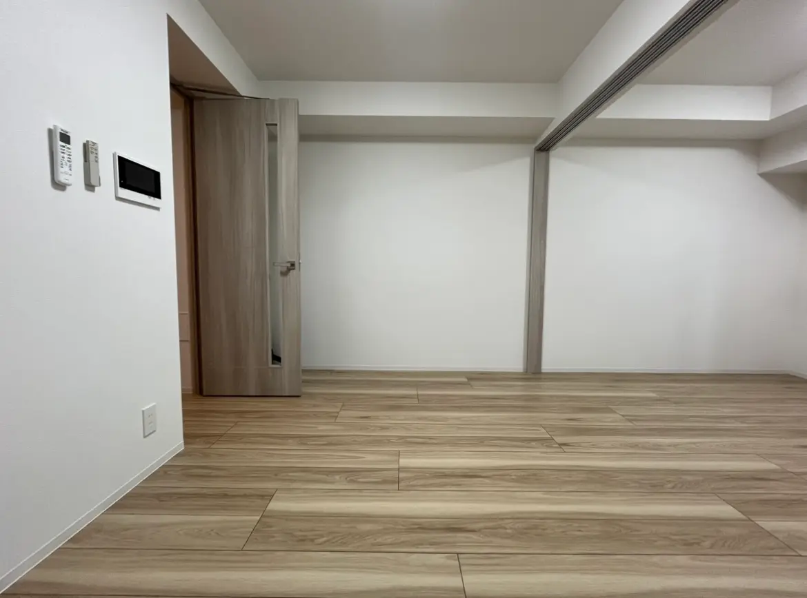 シンプルで洗練されたモダンな部屋、木目調のフローリング、ホワイトの壁とドア