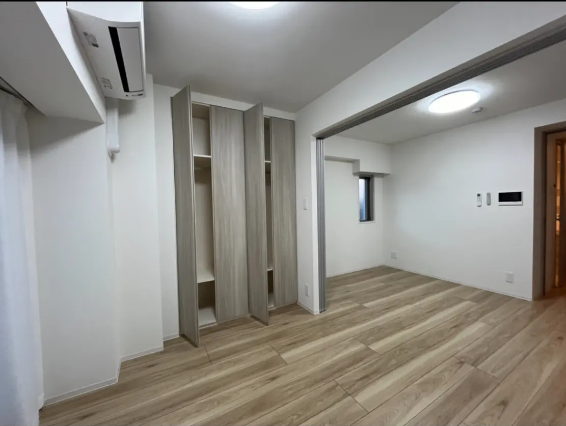 シンプルでモダンなデザインの空の部屋、木目調のフローリング、白い壁、組み込みのクローゼット、エアコン完備