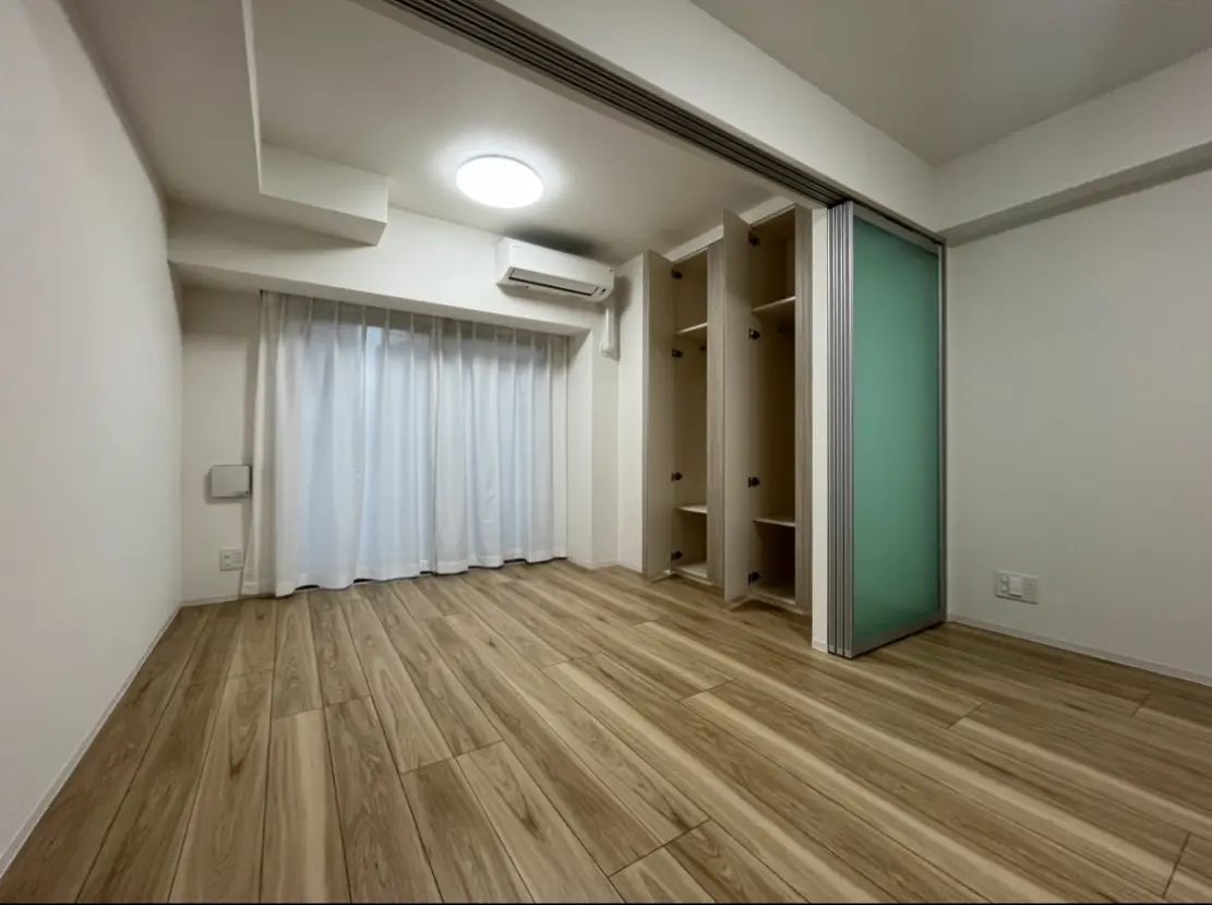 シンプルなデザインの空の部屋、木目調フローリング、白いカーテンとクローゼットがあるインテリア