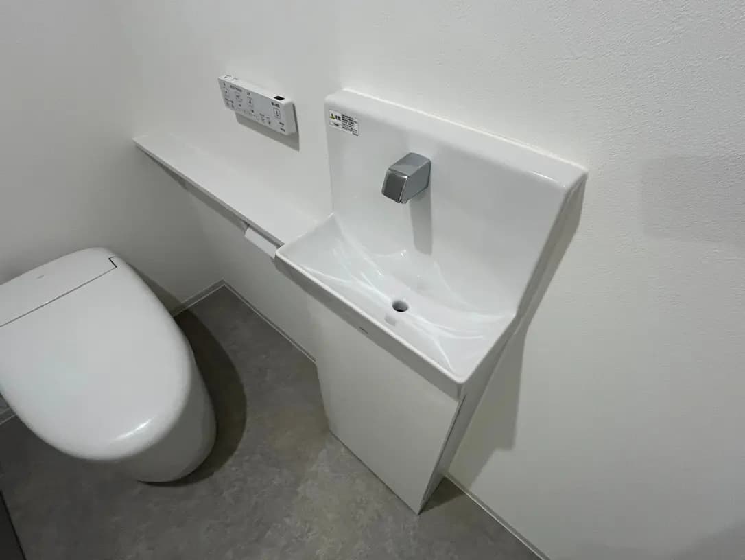 シンプルなデザインのトイレと洗面台、白を基調とした清潔感あるバスルーム